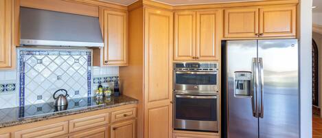 A kitchen with wooden cabinets, stainless steel appliances, and a tiled backsplash.