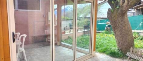 A covered patio with a sliding glass door leading to a stone patio area.