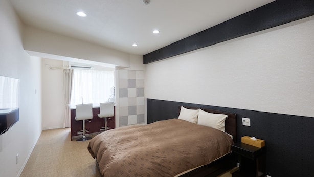 Ein Hotelzimmer mit einem Bett, einem Nachttisch und einem Schreibtisch mit Stuhl.