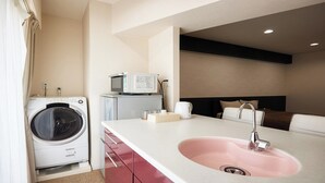 Ein Hotelzimmer mit Waschmaschine, Mikrowelle, Spüle und einem Bett mit Kopfteil.