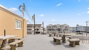 A courtyard with outdoor seating, a building with a window, and a clear sky. - Sun, Sand &Poolside Fun! Beautiful 1BR Beach Condo (North Wildwood)