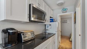 A compact kitchenette with a microwave, toaster, coffee maker, and a sink. - Sun, Sand &Poolside Fun! Beautiful 1BR Beach Condo (North Wildwood)
