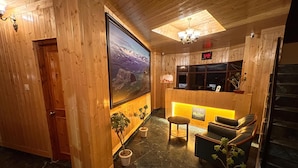 A wooden interior with a reception desk, seating area, and a large framed picture on the wall. - The Jungle Story By Headquarter (Shimla)