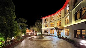 A hotel with a courtyard, multiple floors, and a well-lit entrance. - The Jungle Story By Headquarter (Shimla)