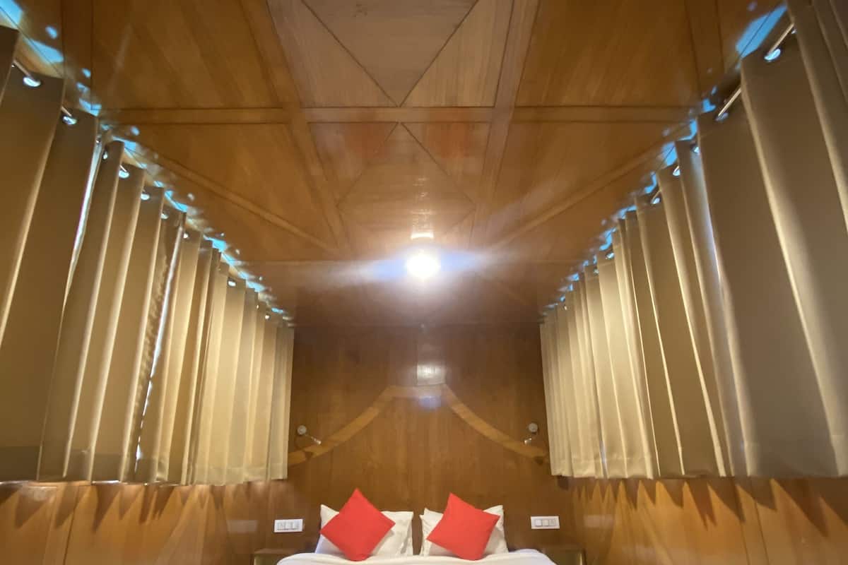 Ein schmales Zimmer mit Holzwänden und einem Bett, das zwischen zwei Vorhängen zentriert ist.