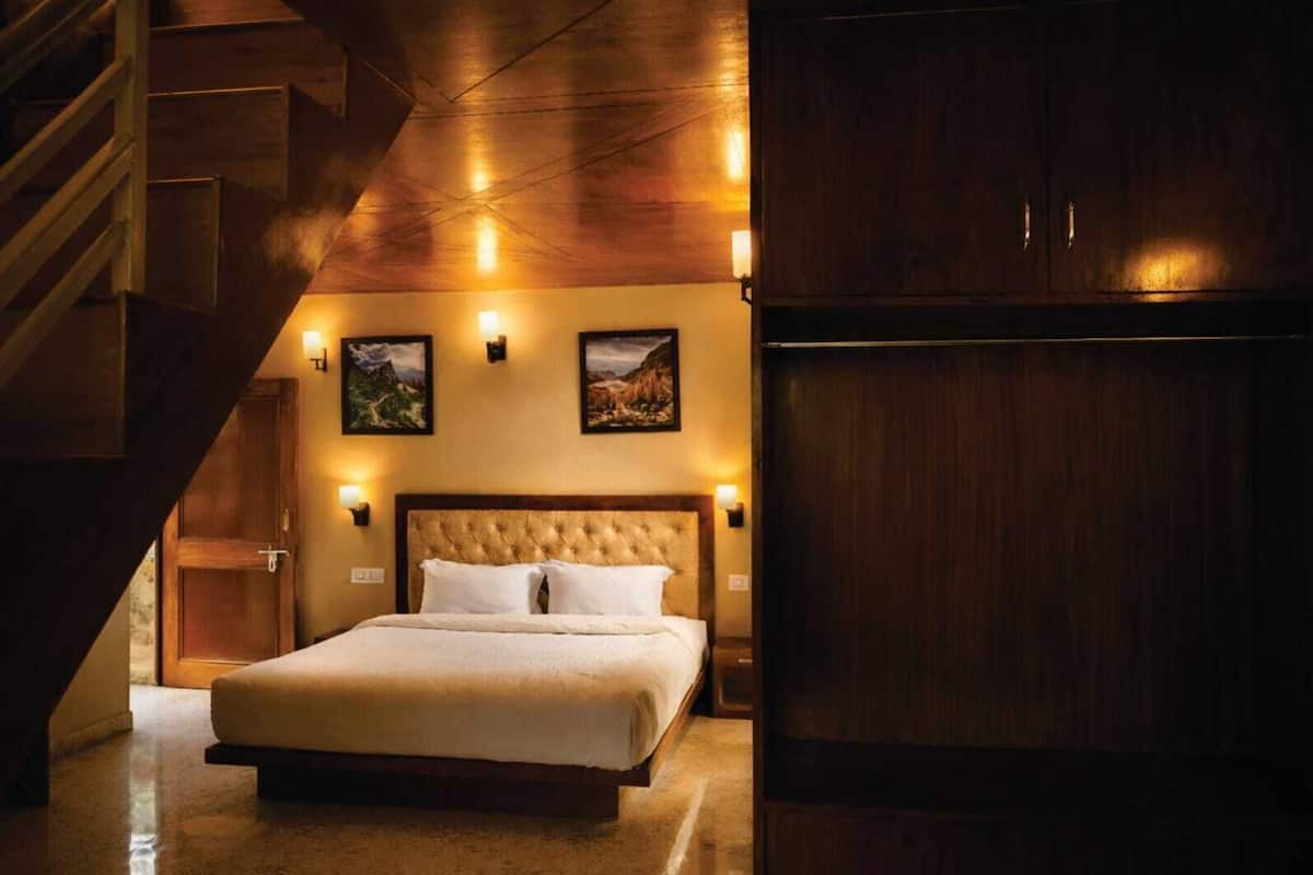 Ein Schlafzimmer mit einem großen Bett, einem Holz-Kopfteil, zwei Wandleuchten und zwei gerahmten Bildern an der Wand.