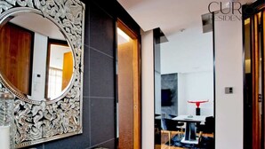 A modern interior with a large ornate mirror, a marble countertop, and a dining area visible through an open doorway. - Luxury Knightsbridge Apartment near Harrods (Greater London)
