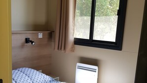 A compact bedroom with a bed, a window, and a wall-mounted heater. - Logement Proche D'ajaccio et des Plages de Porticcio Pour 4 Personnes (Bastelicaccia)
