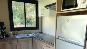 A compact kitchen with wooden cabinets, a built-in microwave, and a refrigerator. - Logement Proche D'ajaccio et des Plages de Porticcio Pour 4 Personnes (Bastelicaccia)