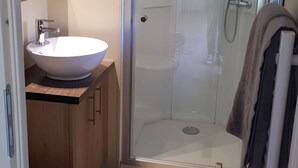 A bathroom with a glass-enclosed shower, a white sink, a toilet, and a towel rack. - Logement Proche D'ajaccio et des Plages de Porticcio Pour 4 Personnes (Bastelicaccia)