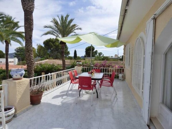 Enjoy a peaceful retreat on this balcony with a table and chairs, surrounded by lush greenery and a beautiful garden view.