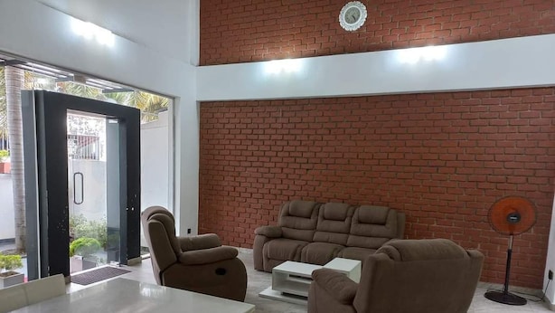 Een woonkamer met een bakstenen muur, een bank, een bijzettafeltje en een ventilator.
