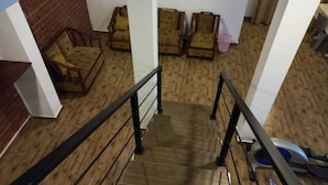 Een trap met een houten vloer en zwarte leuningen, leidend naar een kamer met een bakstenen muur en een bank.