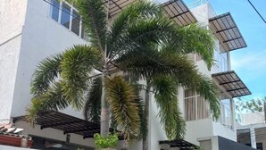 Een modern, tweelaags gebouw met een witte gevel, een overdekt balkon en een garagepoort.