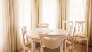 A round dining table with four chairs, a placemat, and sheer curtains.