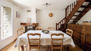 A dining room with a wooden table, chairs, a fireplace, and a staircase. - Maison de Campagne- mas Célestin Avec Piscine 6 Personnes - 3 Chambres (Camaret-sur-Aigues)