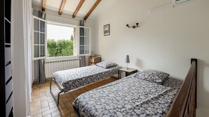 A bedroom with two beds, a window with a view, a radiator, and a wall-mounted lamp. - Maison de Campagne- mas Célestin Avec Piscine 6 Personnes - 3 Chambres (Camaret-sur-Aigues)