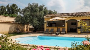 A swimming pool with lounge chairs and a covered patio area. - Maison de Campagne- mas Célestin Avec Piscine 6 Personnes - 3 Chambres (Camaret-sur-Aigues)