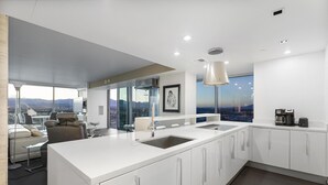 Una cocina moderna con una isla grande, armarios blancos y vistas a la ciudad.