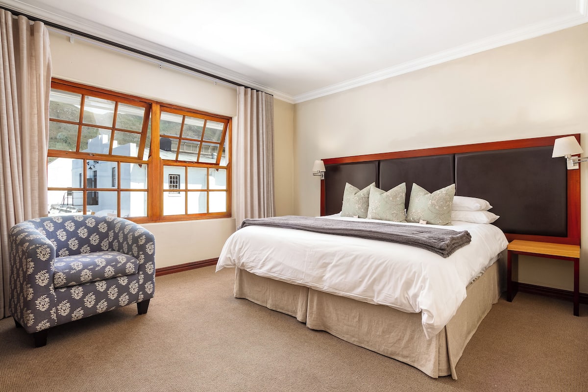 Un dormitorio con una cama grande, una silla y una ventana con cortinas.