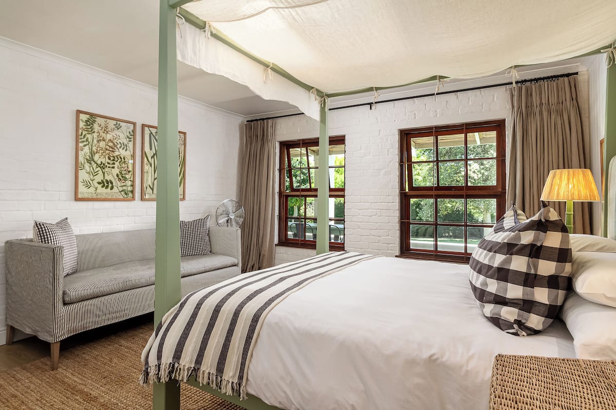Una habitación con cama, sofá, ventilador y ventana con cortinas.