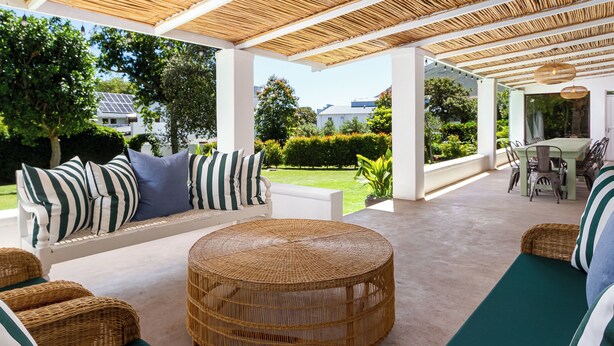 Un espace extérieur abrité, aménagé avec des meubles en osier et offrant une vue sur le jardin.