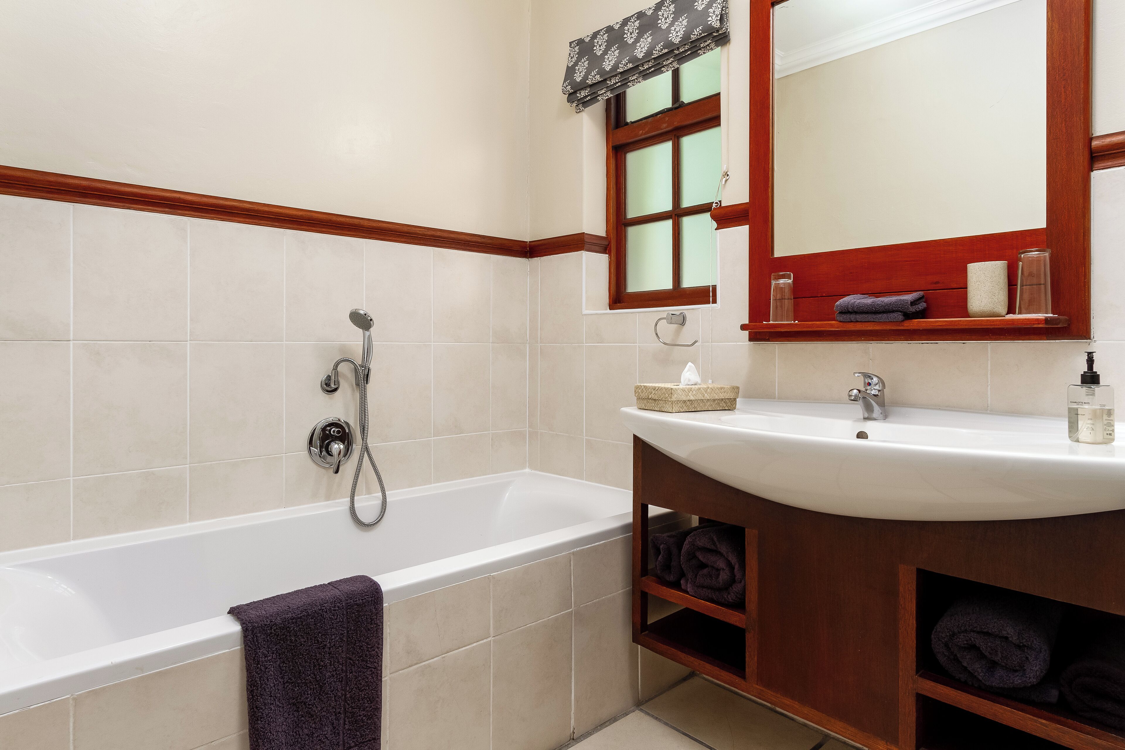 Un baño con bañera, lavamanos, espejo y ventana con vistas al exterior.