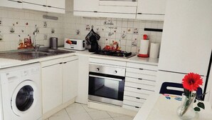 Une cuisine moderne avec des meubles blancs, un lave-linge, un four et une machine à café.
