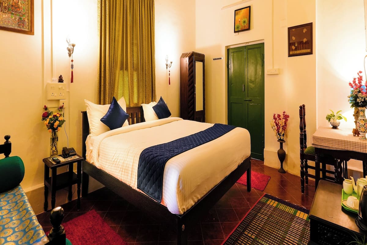 A neatly arranged hotel room with a bed, a desk, a chair, and a dining table.