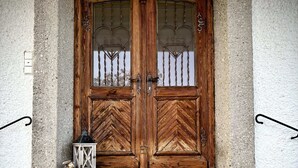 A wooden double door with glass panels and a lantern on the steps.