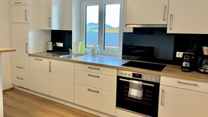 A modern kitchen with white cabinets, a stainless steel sink, a coffee maker, and an oven.