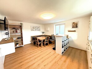 Un espace de vie compact comprenant un coin repas, des étagères intégrées et une fenêtre.