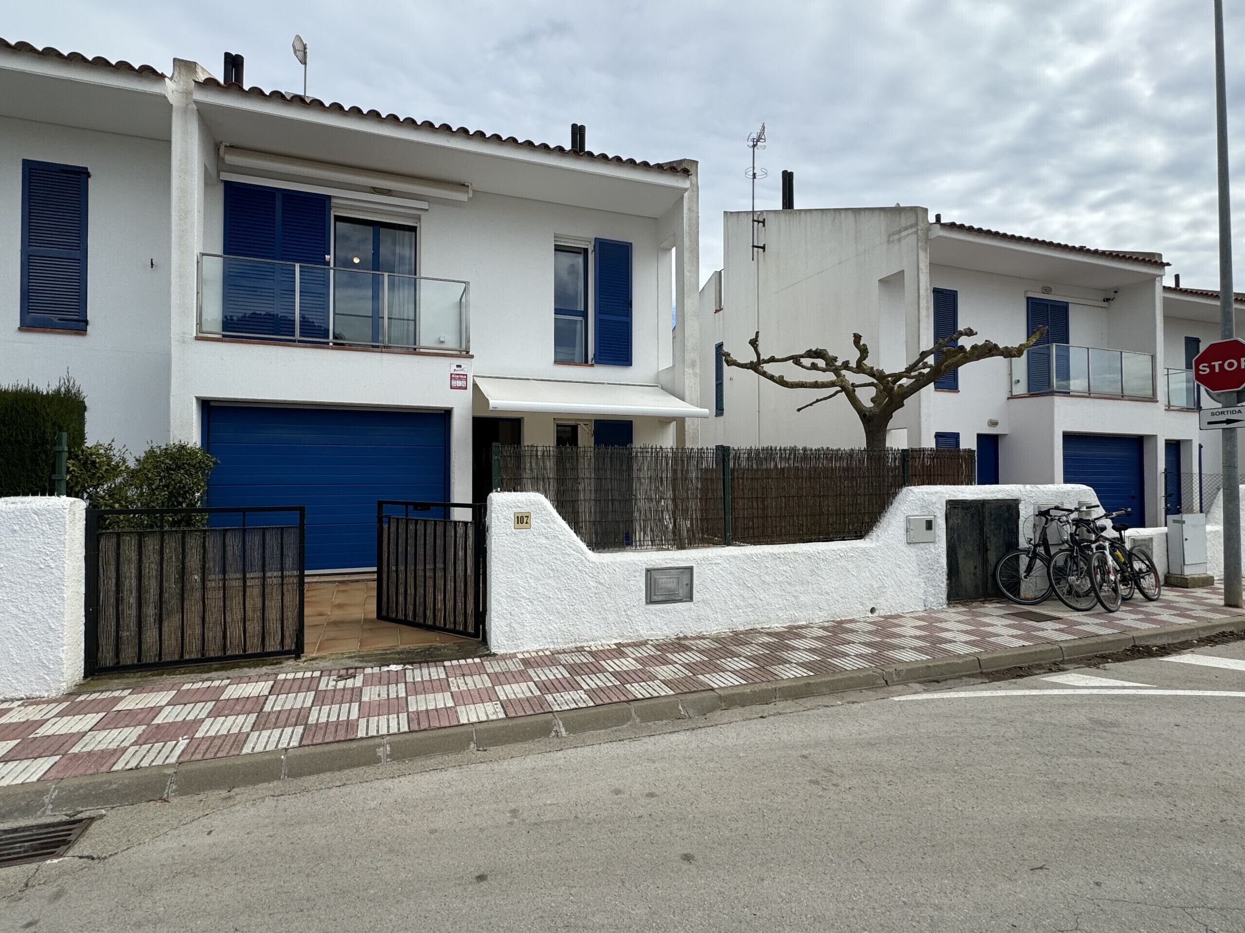 A residential building with a white facade, blue shutters, and a gated entrance.