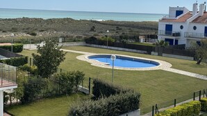 A residential property with a swimming pool, a view of the sea, and a well-maintained lawn.