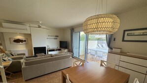 A modern living room with a sofa, TV, and dining area with chairs.