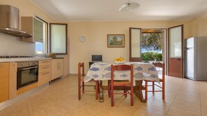 A kitchen with a dining table, chairs, and a refrigerator. - 3846 Villetta Le Largure A by Barbarhouse (Melendugno)