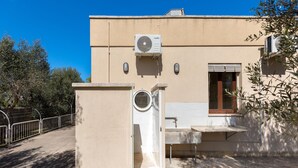 A building with a beige exterior, a window with a wooden shutter, and an air conditioning unit mounted on the wall. - 3846 Villetta Le Largure A by Barbarhouse (Melendugno)
