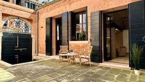 A courtyard with a black gate, a small table with chairs, and a potted plant. - Spezier Canal View (with common terrace) (Venecia)
