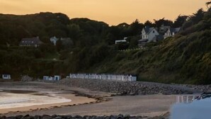 Un paisaje costero con una playa, costa rocosa y casas al fondo.