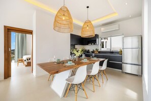 A modern kitchen with a dining area, featuring a wooden table, white chairs, and pendant lighting. - 3 Bed Close To Fisherman Village KBR18 (Koh Samui)