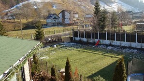 Un espace extérieur clos, doté d’une aire de jeux, d’un bâtiment avec un toit en pente et d’un paysage vallonné en arrière-plan.