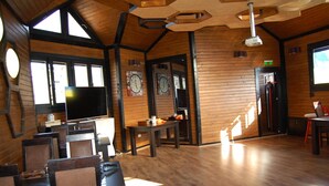 Un intérieur rustique avec des murs et des planchers en bois, une grande horloge et un téléviseur.