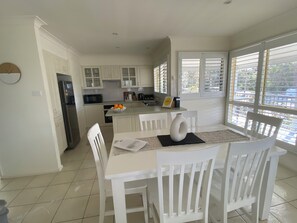 Modern kitchen with a microwave, stainless steel refrigerator, and a small island with a sink and fruit.