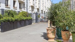 Un edificio residencial con balcones, entrada protegida y plantas en macetas.