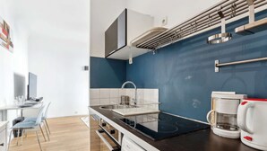 Una cocina moderna con encimera negra, estufa integrada, un fregadero con escurreplatos y una cafetera.