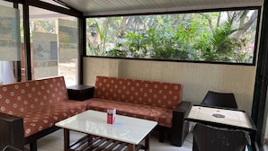 A room with a sofa, a coffee table, and a small table with chairs. - O Nest Beach Front Villa (Alibag)
