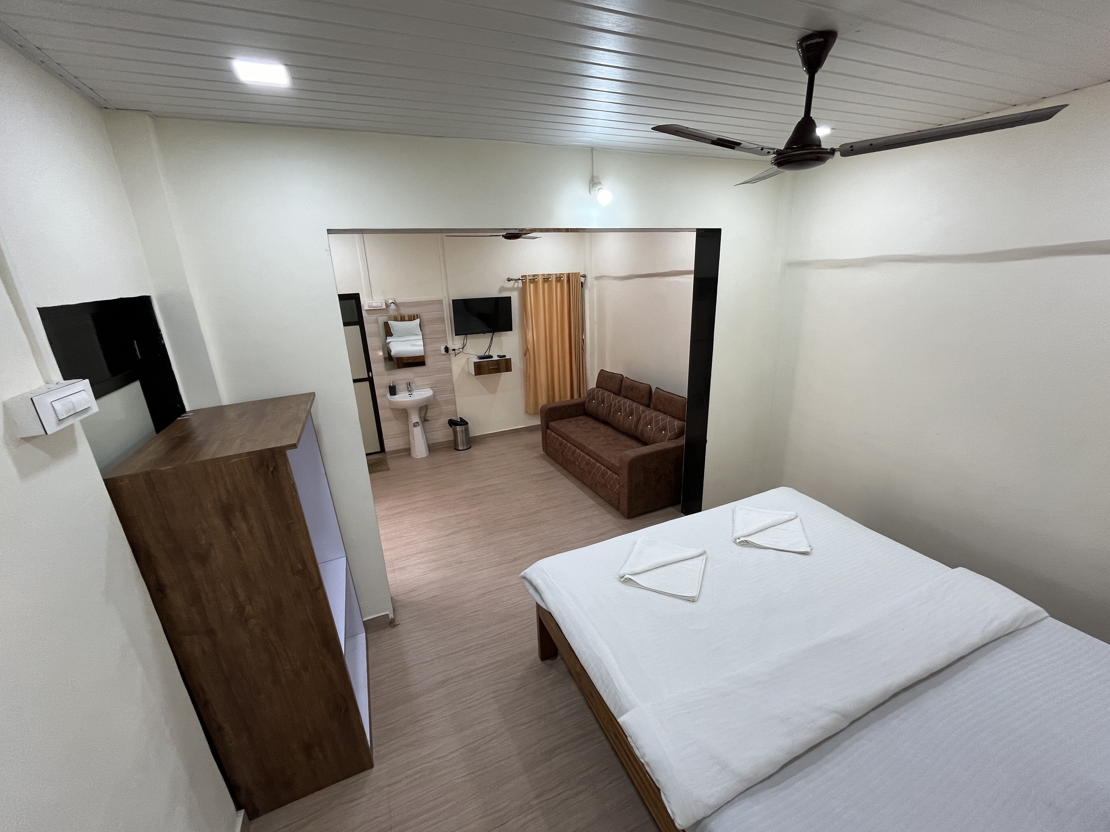 Une chambre d’hôtel équipée d’un lit, d’un bureau, d’un canapé, d’une télévision, d’un ventilateur de plafond et d’une salle de bain.
