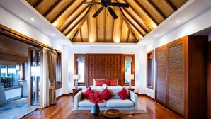 Una habitación amplia con techo de madera, un sofá con cojines rojos y una mesa de centro.