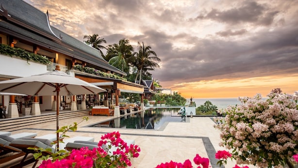 Un resort con piscina, sillones de descanso y vistas al atardecer.