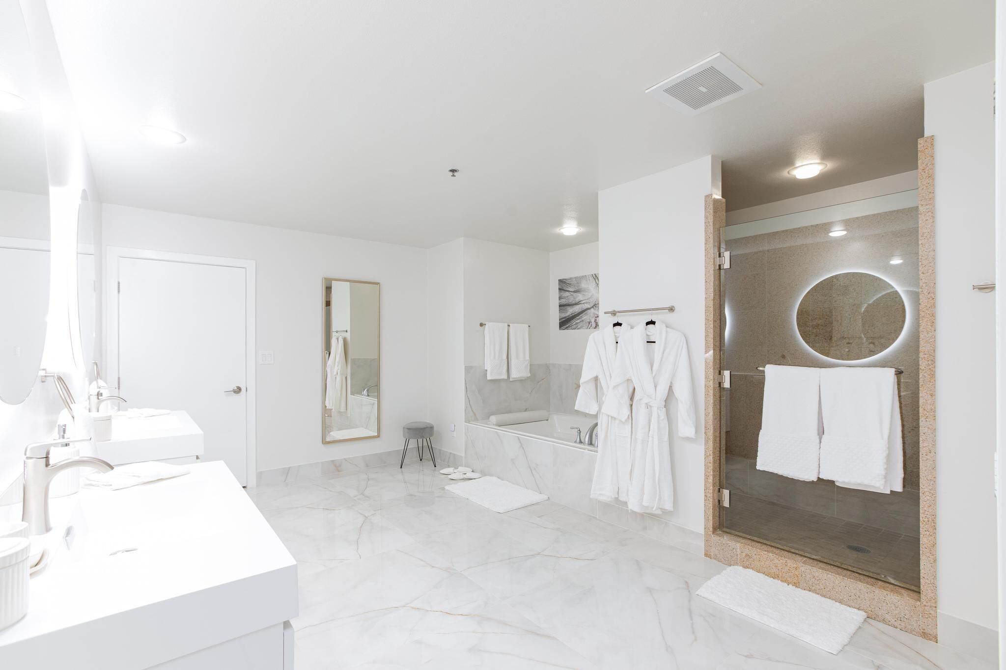 A modern bathroom with a large mirror, a bathtub, and a glass-enclosed shower area.